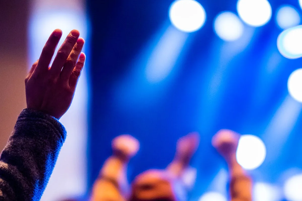 Concert audience beneath stage lighting (representative image)